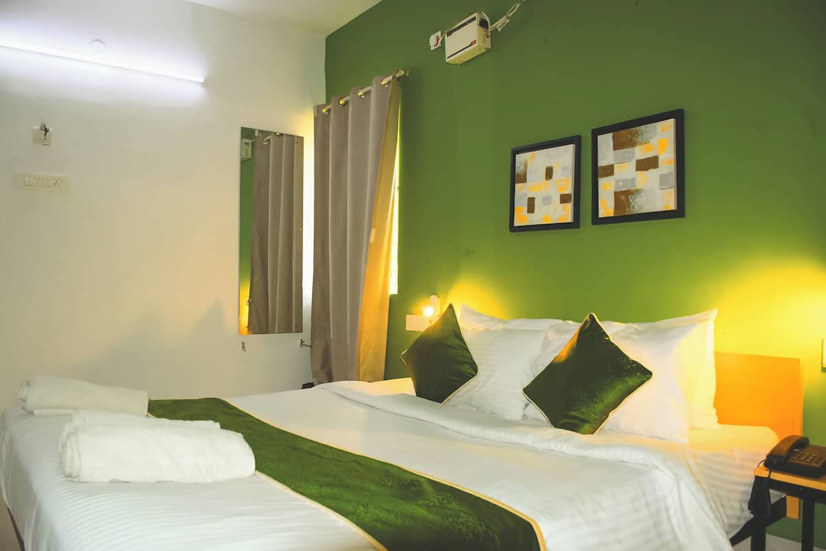 Una habitació d'hotel amb un llit, una paret verda, dos quadres emmarcats, un telèfon i una finestra amb cortines.