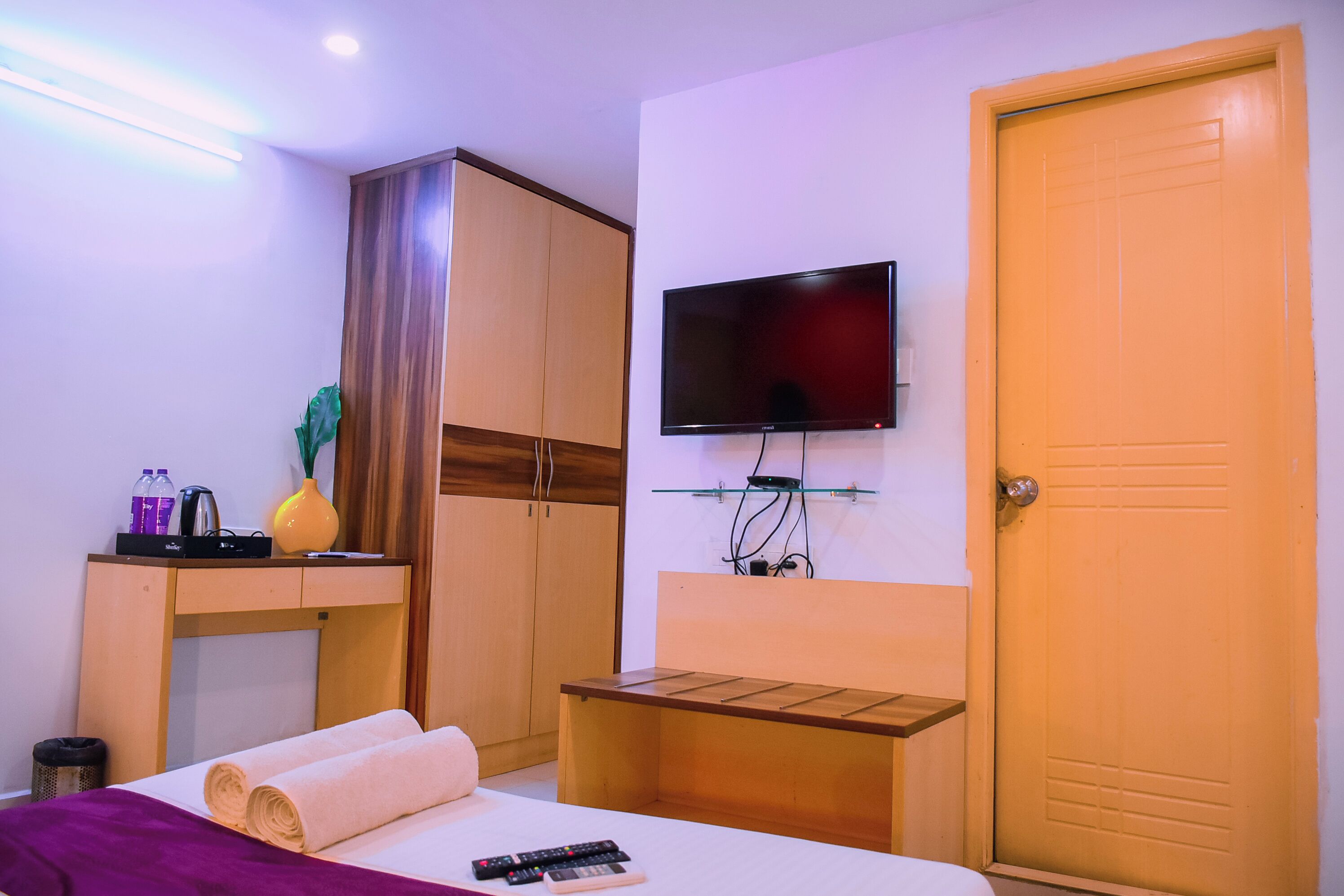 Una habitación de hotel con cama, escritorio, televisor, armario y puerta.