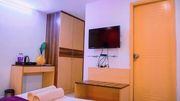 Una habitación de hotel con cama, escritorio, televisor, armario y puerta.