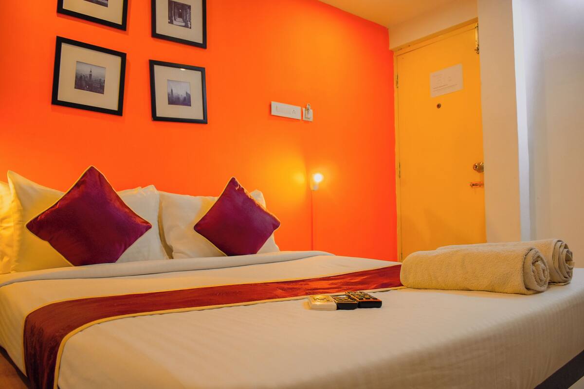 Una habitació d'hotel amb un llit, almoines, una manta, un comandament a distància i una porta.