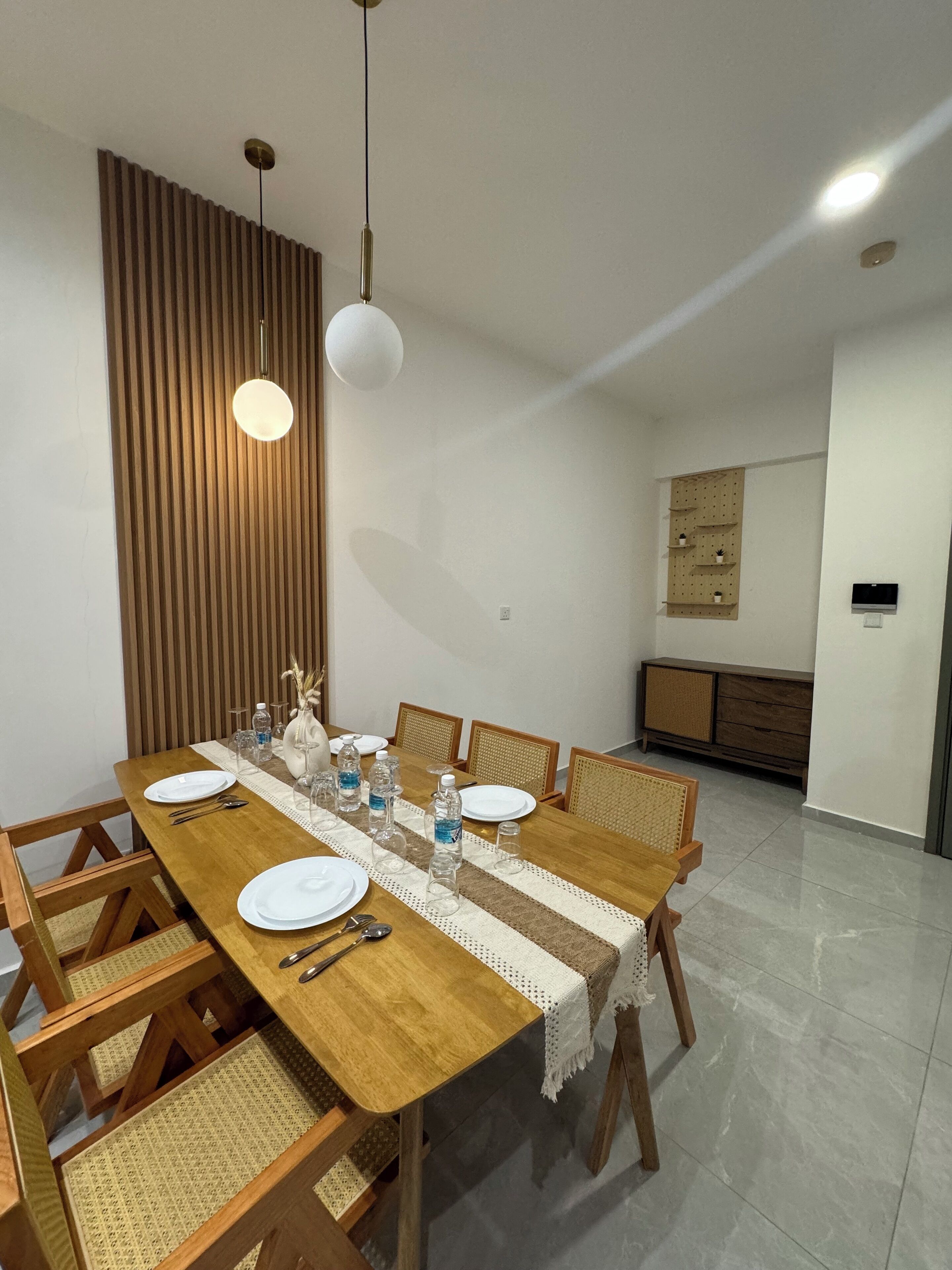 A dining area with a wooden table set for six, surrounded by wicker chairs.
