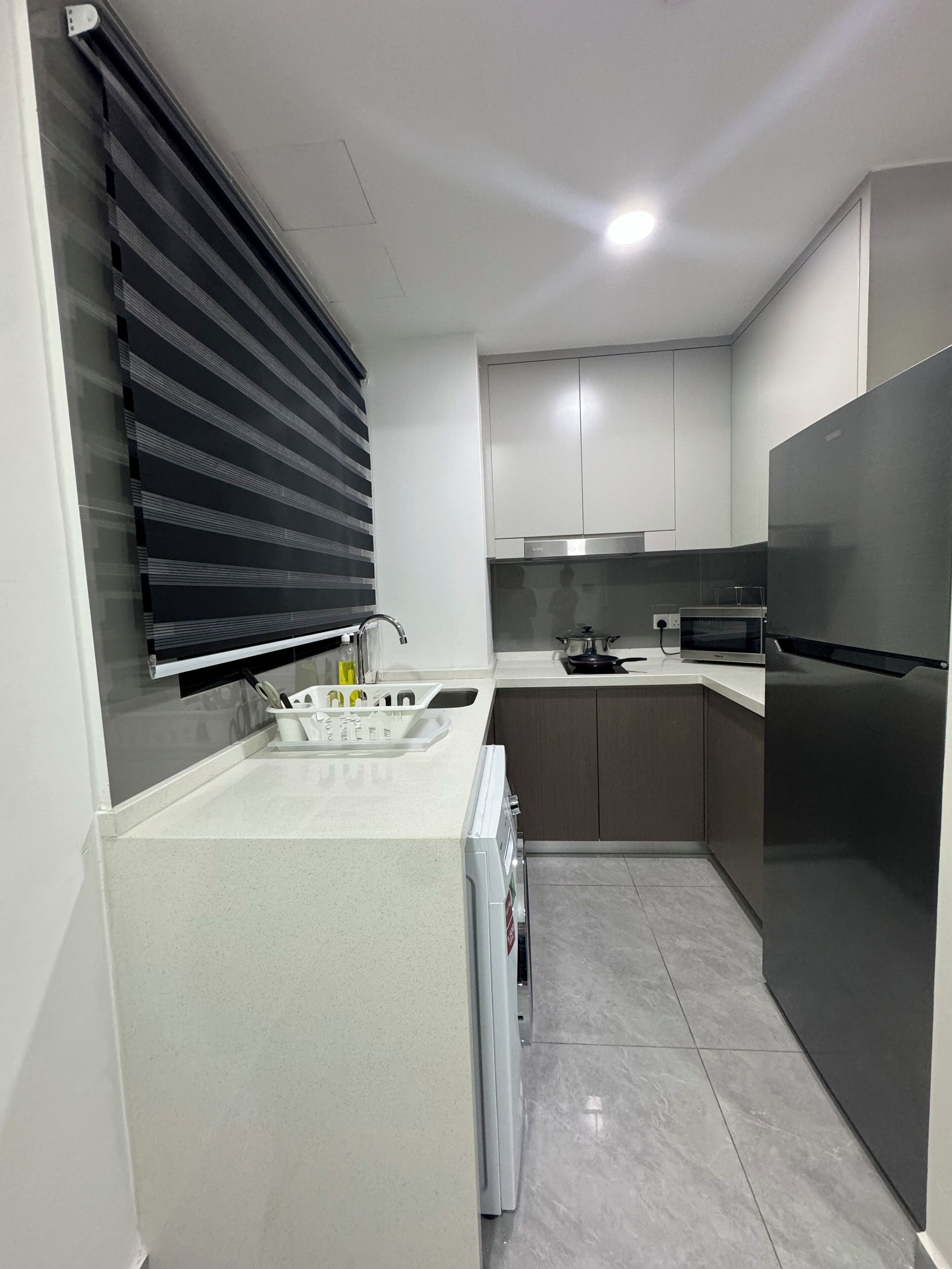 A modern kitchen with a built-in oven, microwave, and stainless steel refrigerator.