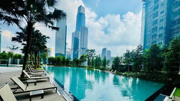 A swimming pool with lounge chairs, surrounded by greenery and tall buildings in the background. - Agile Premium Service Suite KL (Kuala Lumpur)
