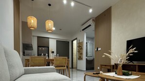 A modern living room with a large grey sofa, a wooden dining table, and two hanging light fixtures. - Agile Premium Service Suite KL (Kuala Lumpur)