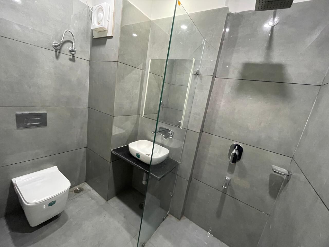 A modern bathroom with a glass-enclosed shower, a white sink, and a toilet.