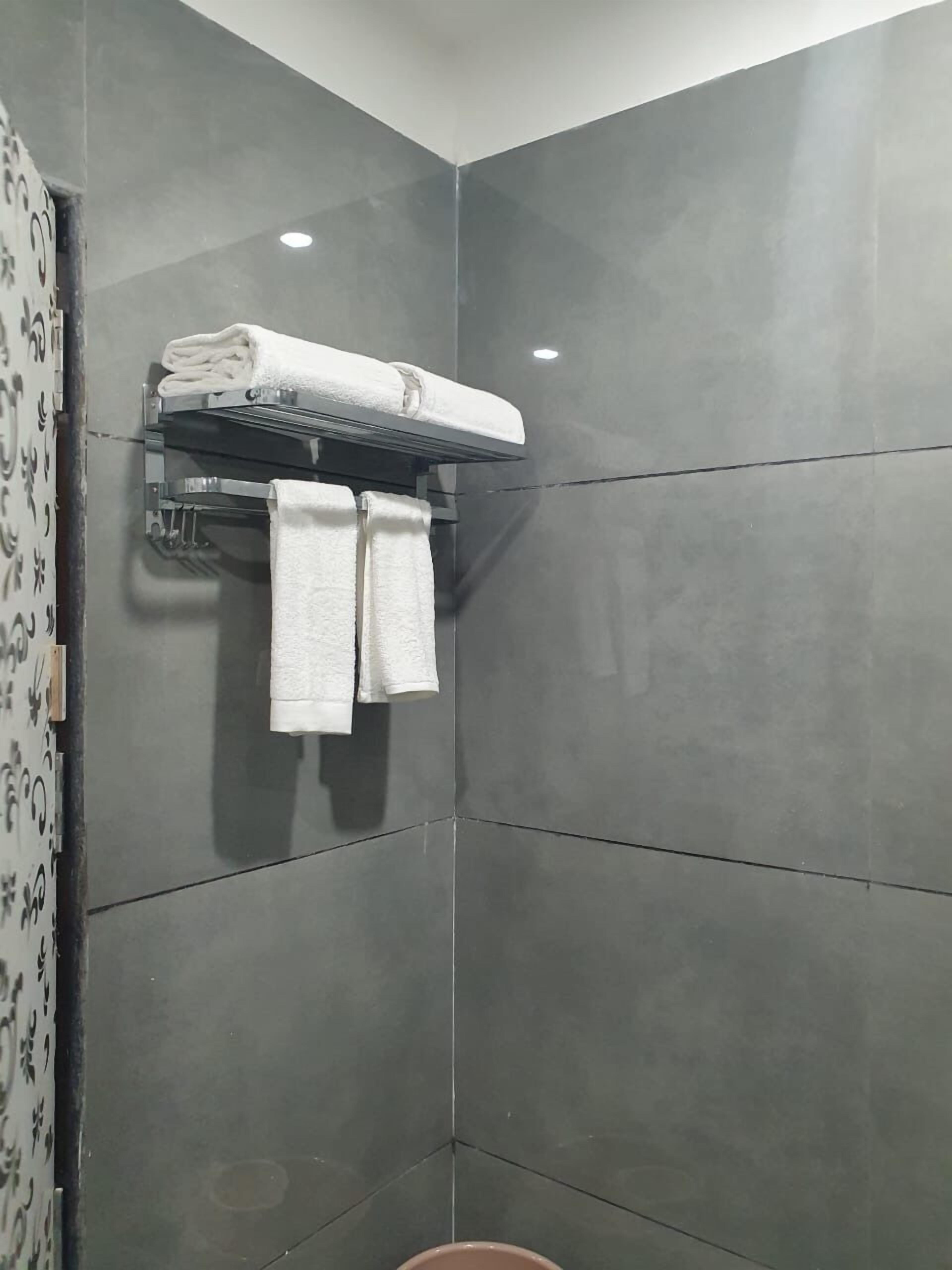 Un baño moderno con baldosas grises, un perchero con dos toallas y una zona de ducha.