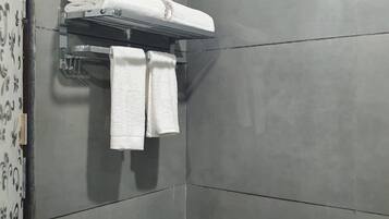 Un baño moderno con baldosas grises, un perchero con dos toallas y una zona de ducha.