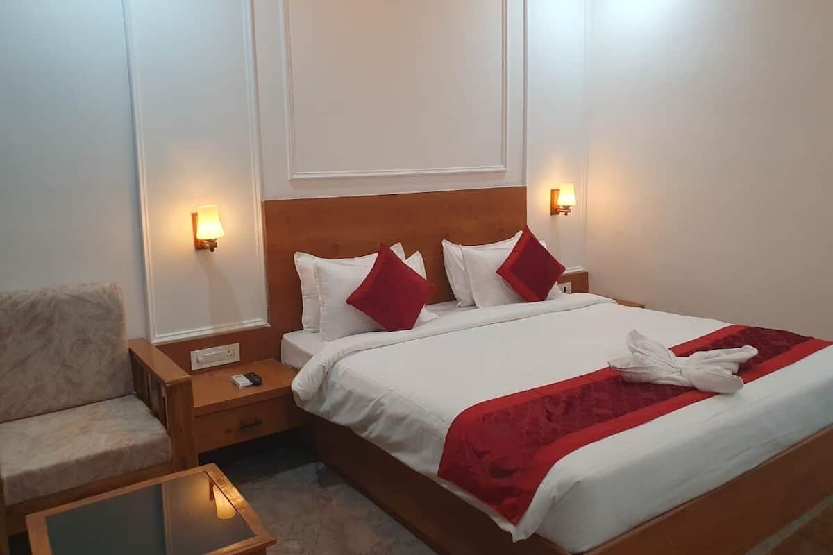 A hotel room with a bed, a nightstand, a chair, and a small table.