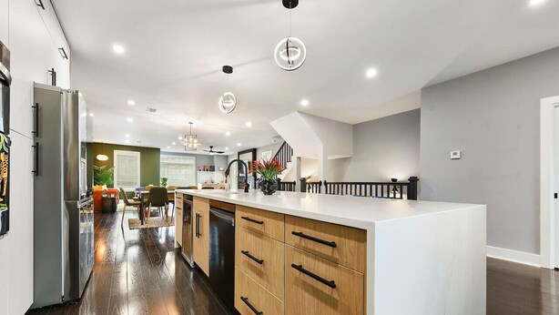 Une cuisine moderne dotée d’un îlot central, de meubles en bois et d’un réfrigérateur en acier inoxydable.