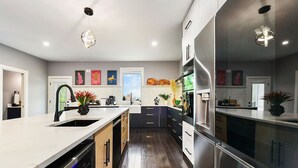 Une cuisine moderne dotée d’un îlot central, d’appareils électroménagers en acier inoxydable et d’œuvres d’art décoratives murales.