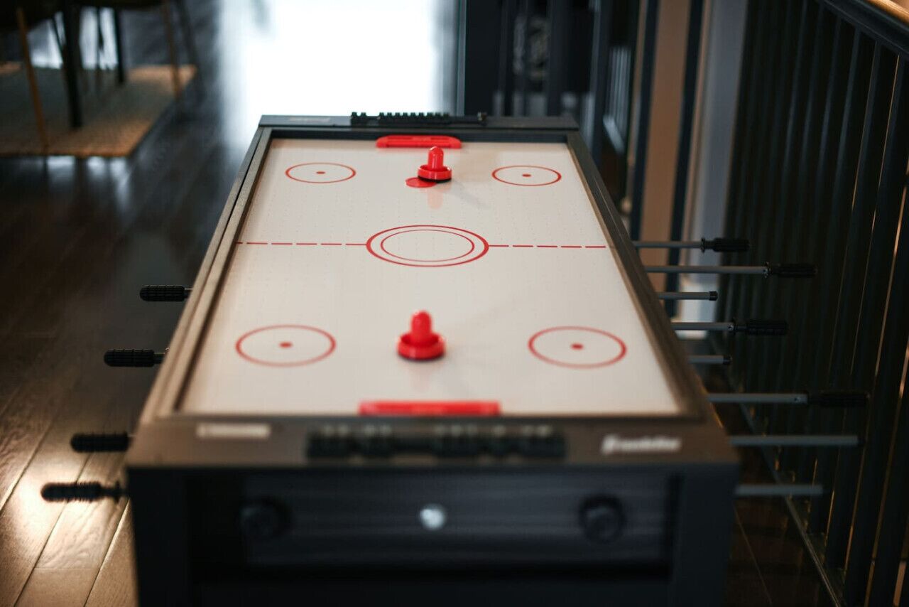 Une table de baby-foot avec quatre joueurs rouges et un joueur rouge au centre, le tout entouré de tiges noires.