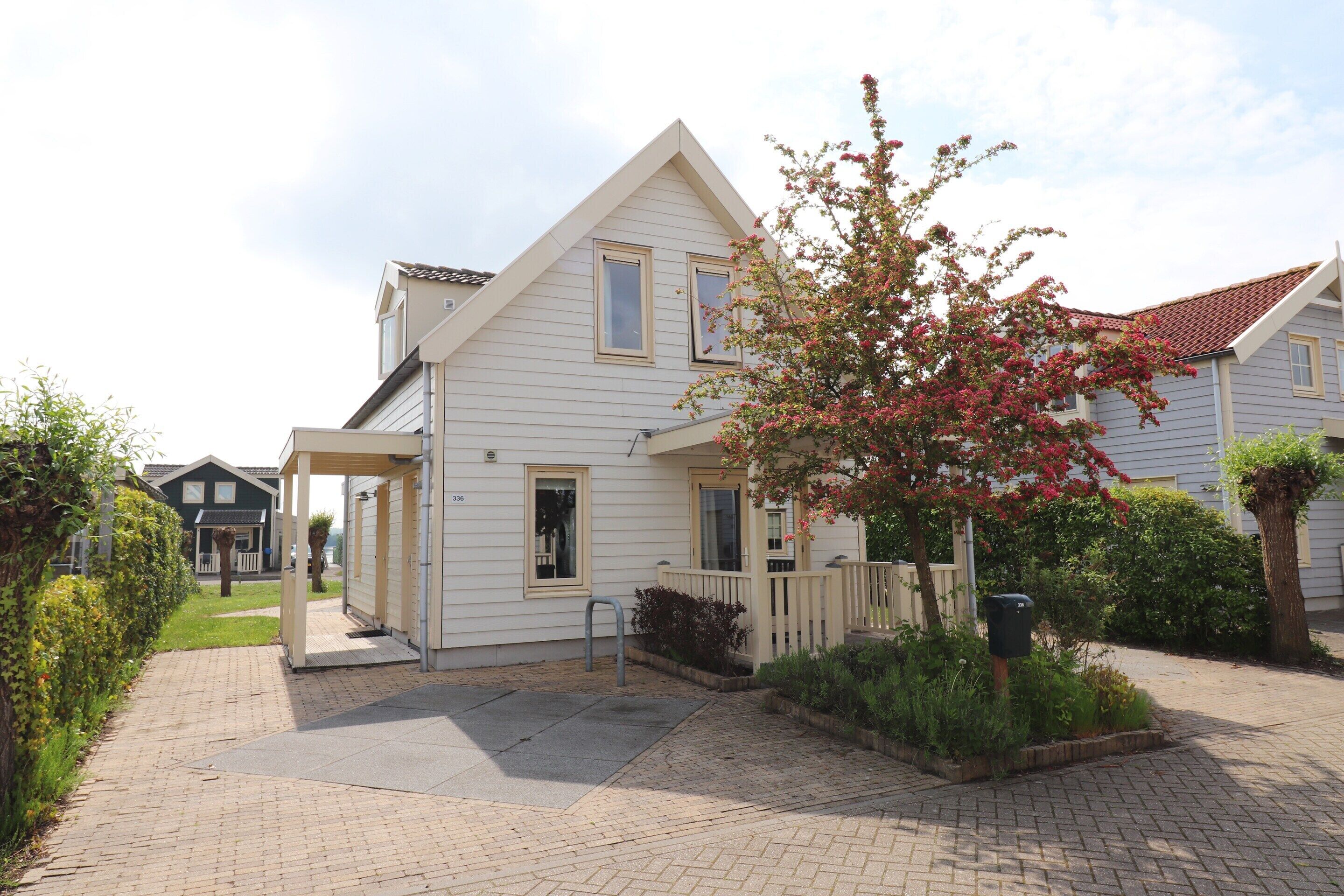 A two-story house with a covered porch and a small garden.