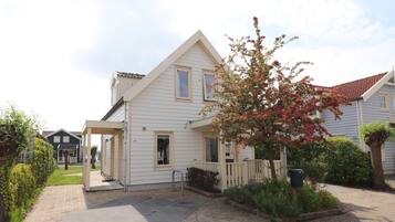 A two-story house with a covered porch and a small garden.