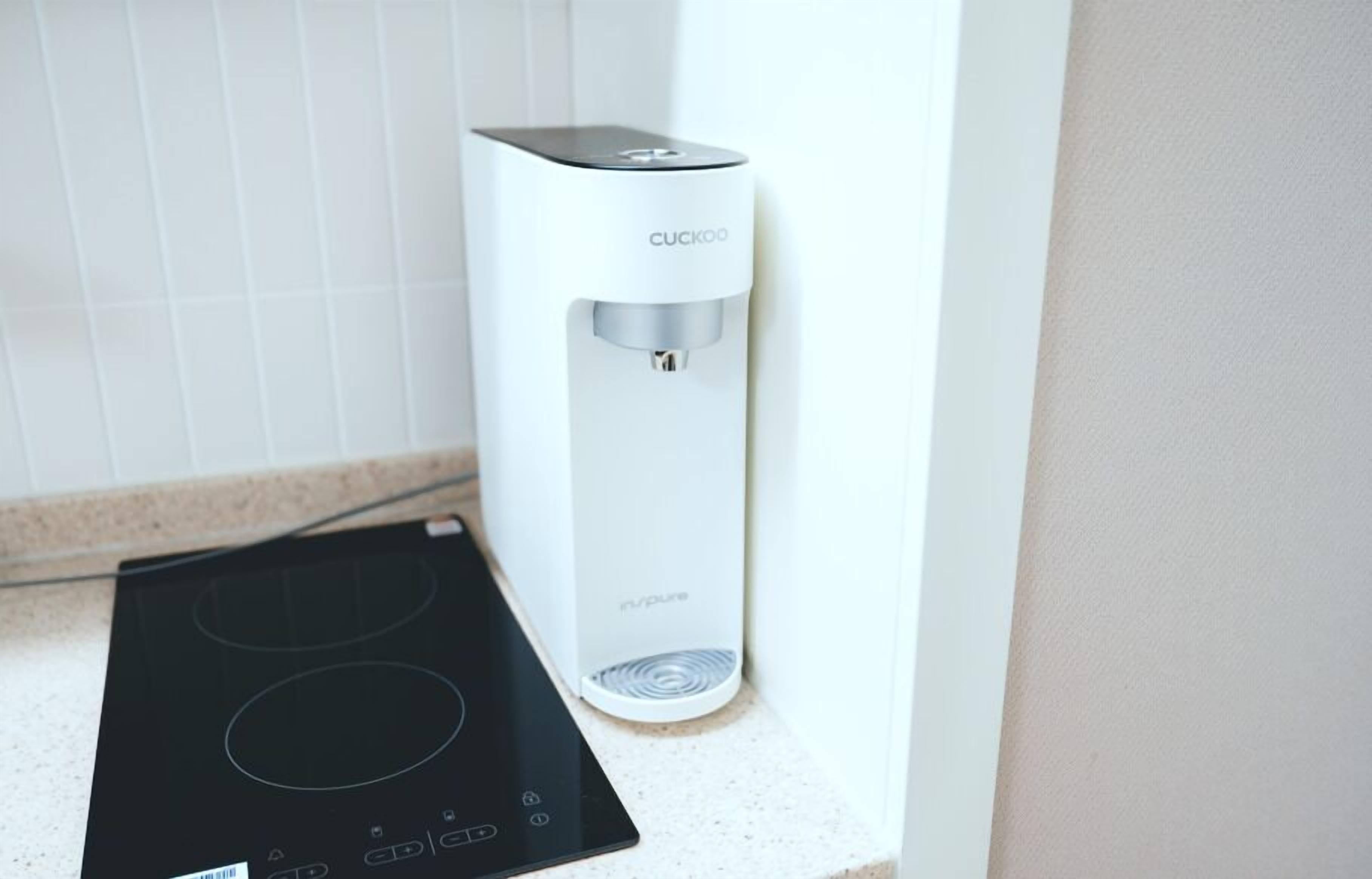 A modern kitchen with a white countertop, a built-in water dispenser, and a black induction cooktop.