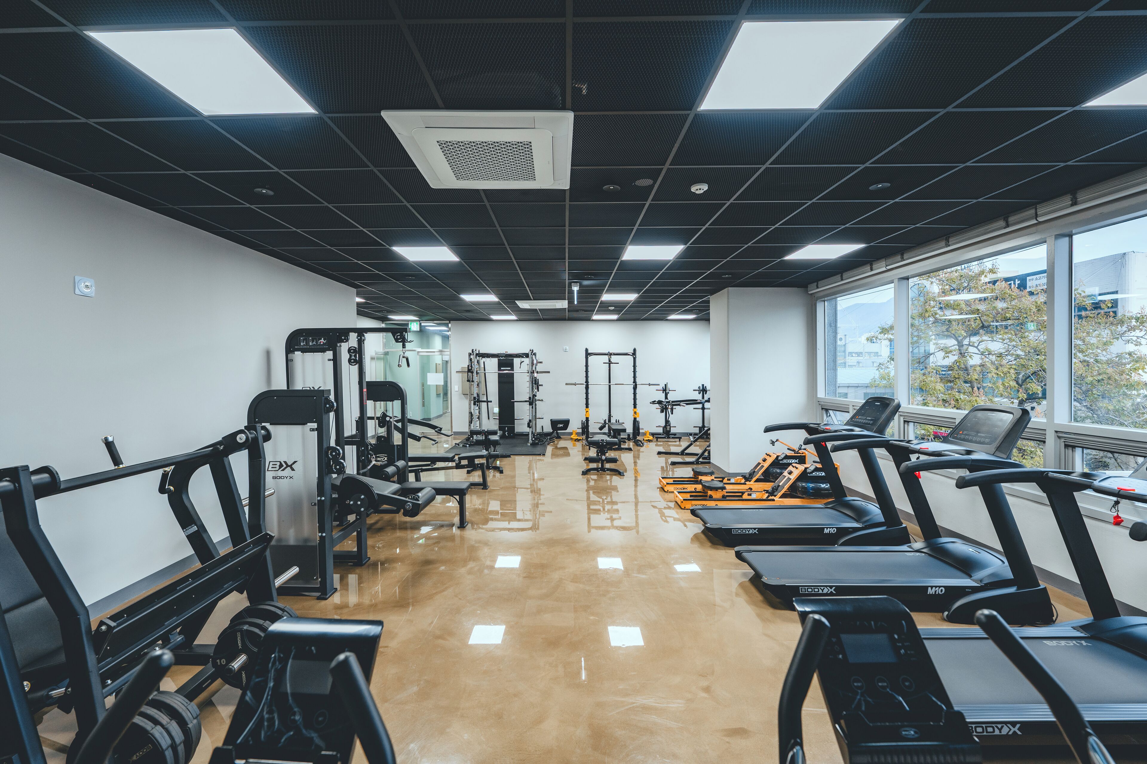 A gym with treadmills, weight machines, and a mirror wall.