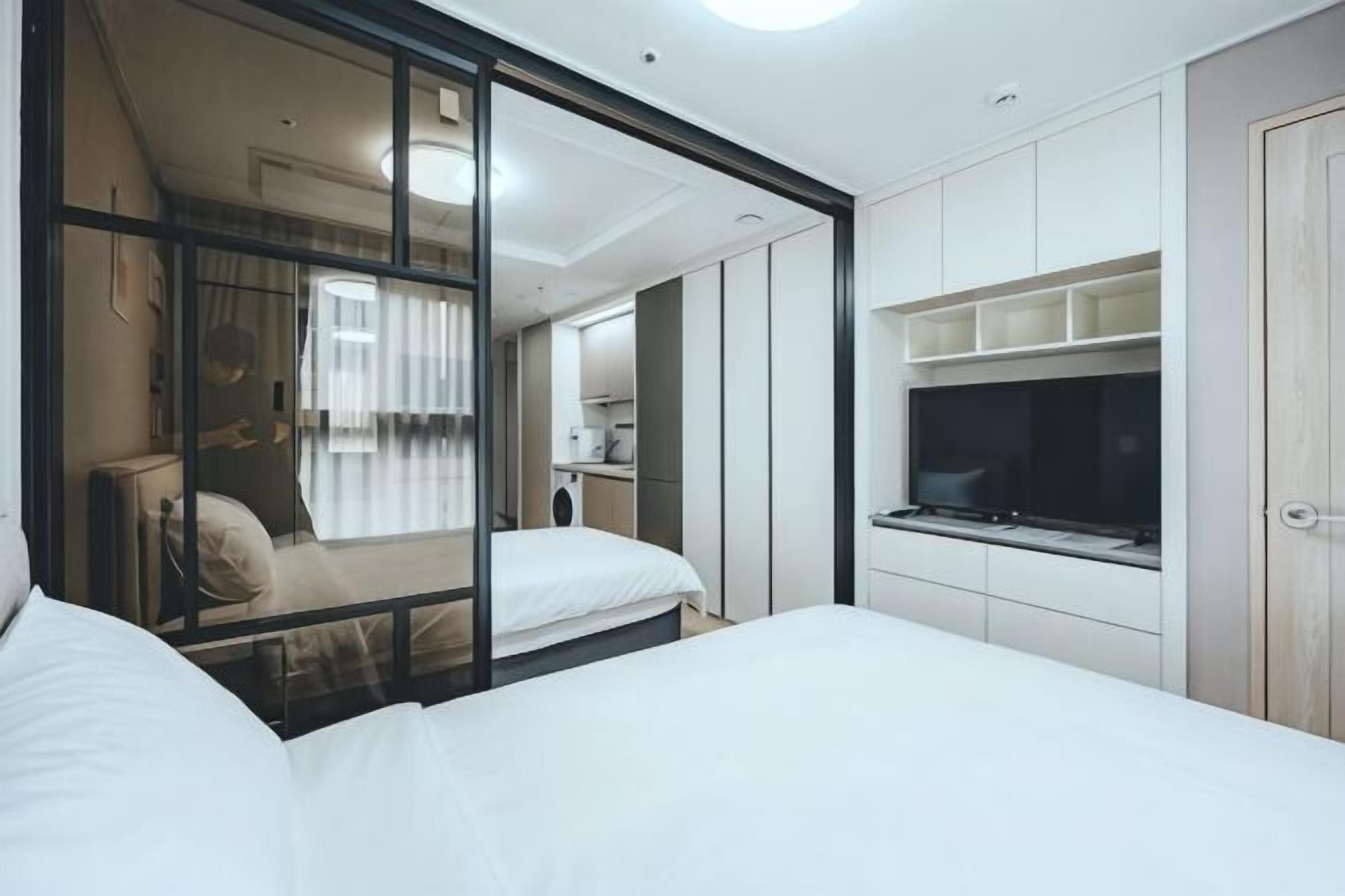 Une chambre d’hôtel moderne dotée d’un grand lit, d’une télévision et d’une porte-fenêtre coulissante donnant sur la salle de bain.
