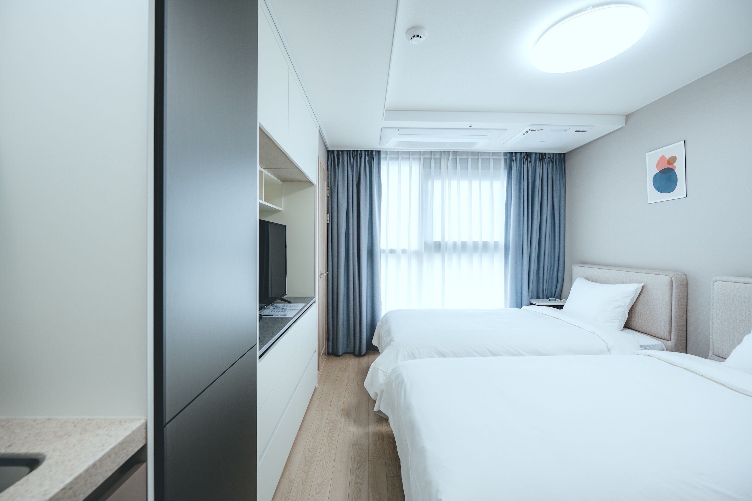 A hotel room with two beds, a desk, and a television.