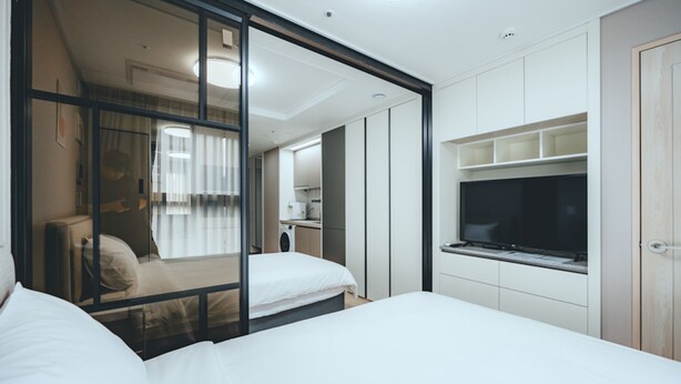 Een moderne hotelkamer met een bed, een televisie en een schuifdeur naar een badkamer.
