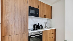 Una cocina compacta con armarios de madera, un microondas, una cafetera y un horno.