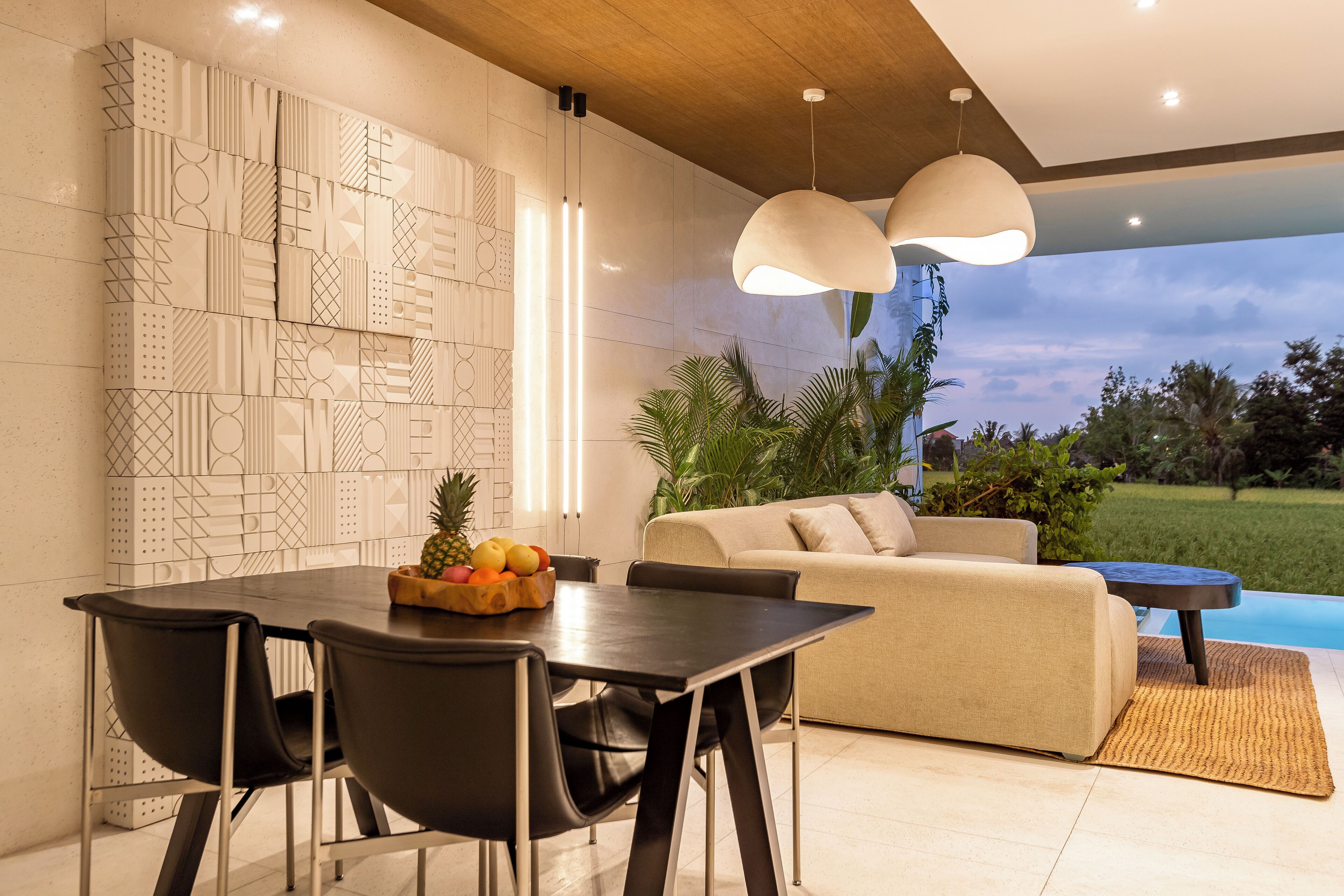 Un comedor moderno con una mesa y sillas, un sofá, y vistas a una piscina y zonas verdes.
