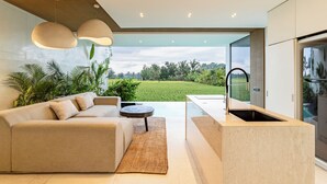 A modern kitchen with a large island, a built-in sink, and a view of a lush garden. - Azure 2BR Villa in Ubud Rice Field views (Ubud)