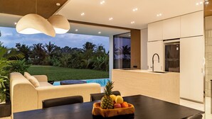 A modern kitchen with a built-in oven and a dining area with a table and chairs. - Azure 2BR Villa in Ubud Rice Field views (Ubud)