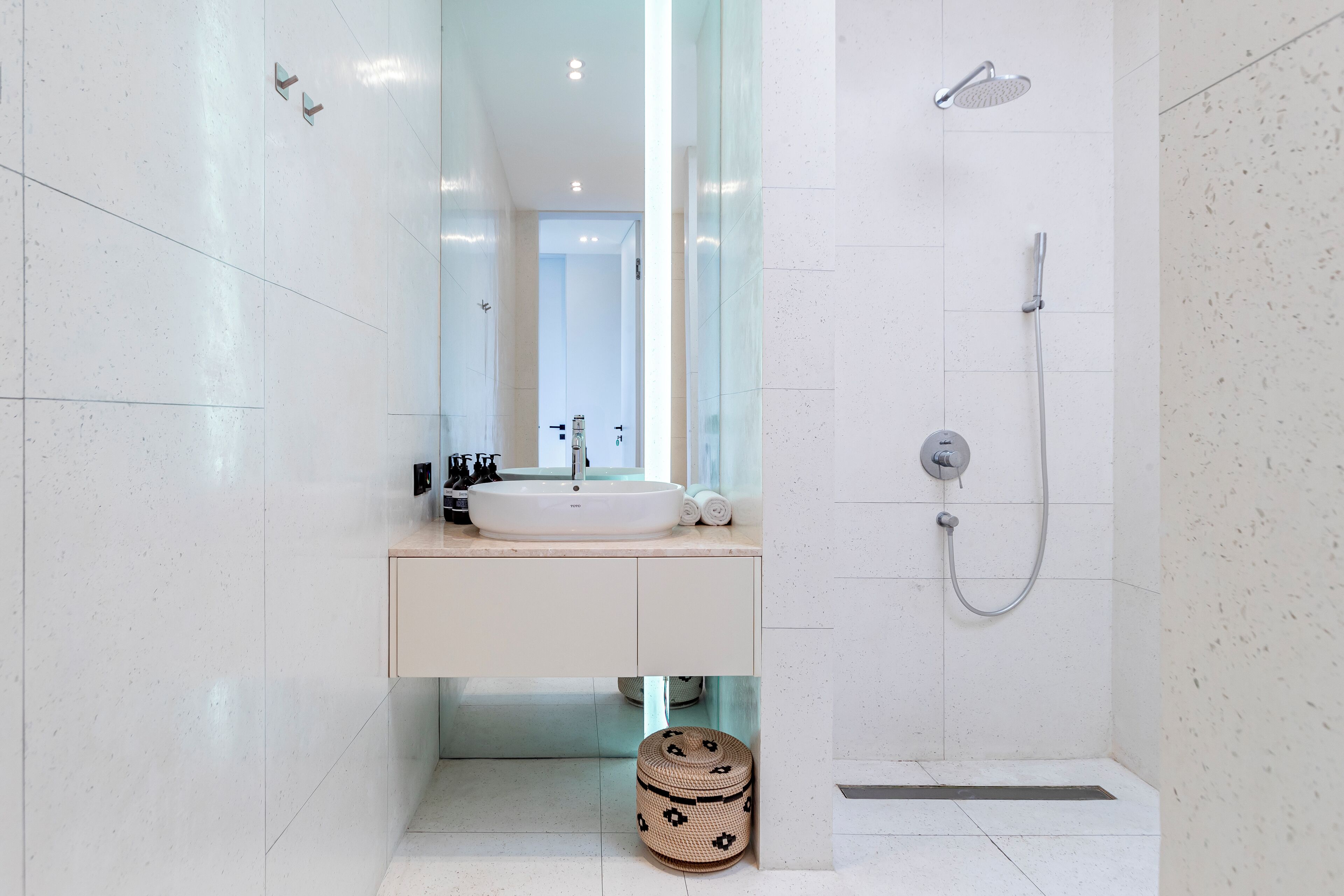 Un baño moderno con un espejo grande, un lavabo blanco y una zona de ducha.