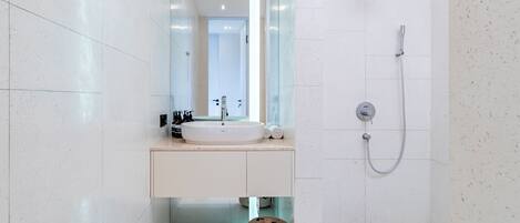 Un baño moderno con un espejo grande, un lavabo blanco y una zona de ducha.