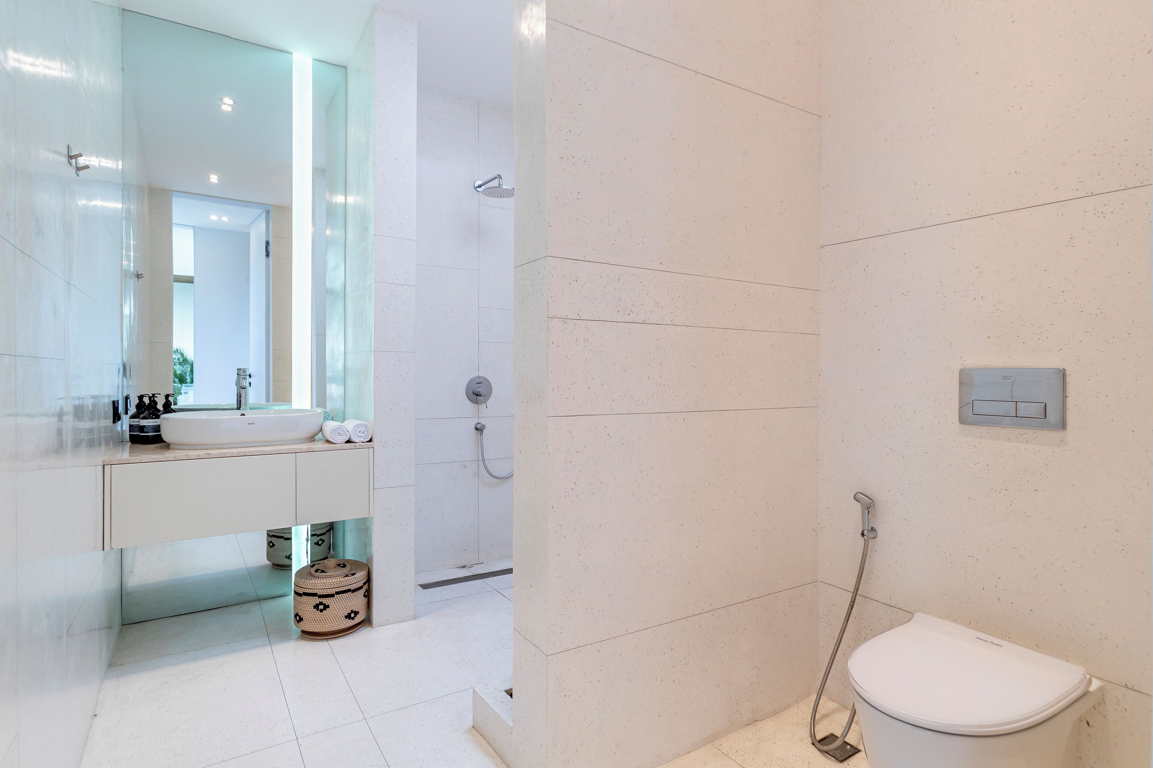 A modern bathroom with a white sink, mirror, and toilet.