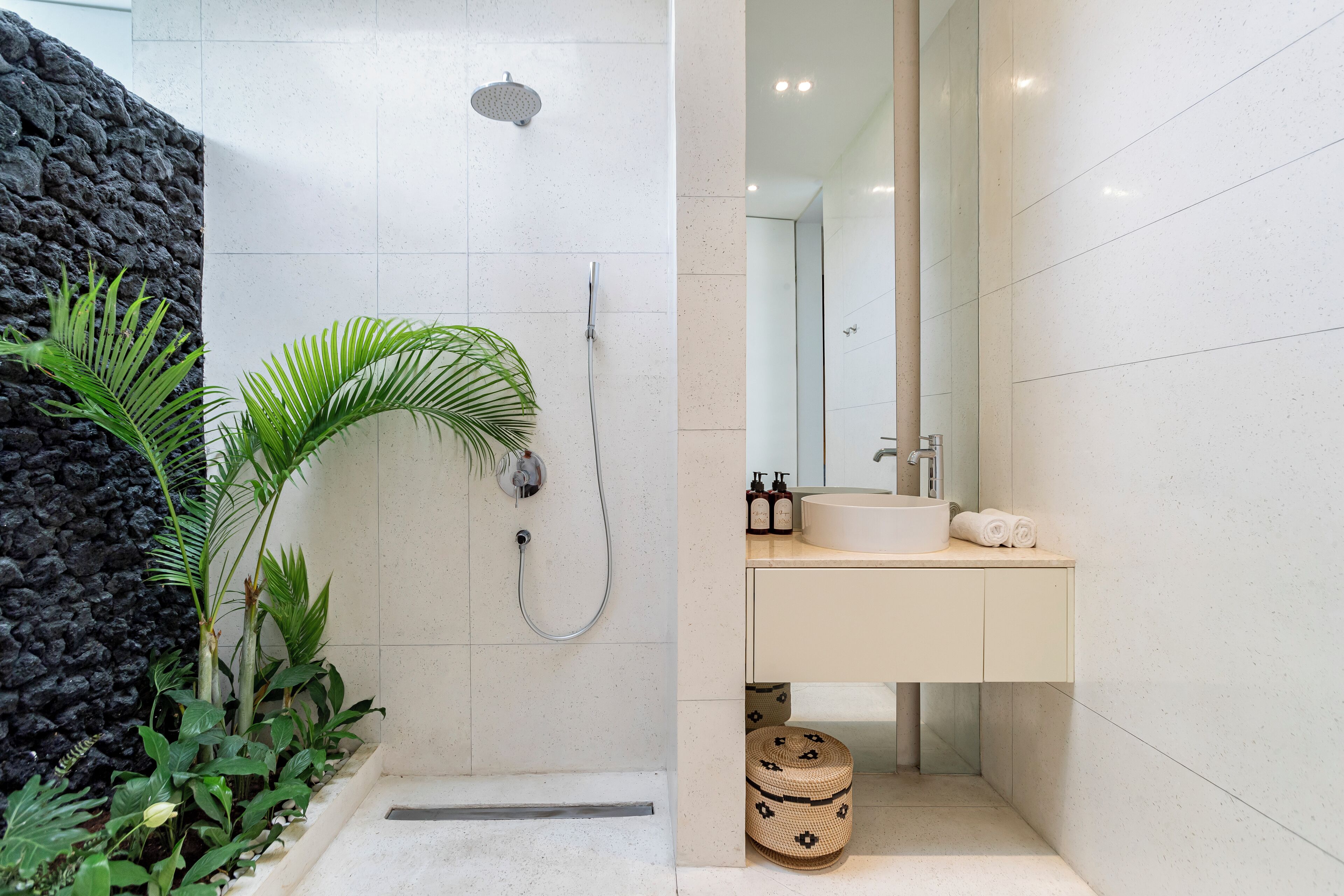 Un baño moderno con ducha, lavamanos y espejo.