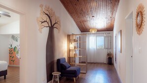 A hallway with a wooden ceiling, a blue chair, a small stool, and a bookshelf. - Résidence tamarin - nature lovers - sea and mountain views (LA RIVIERE)