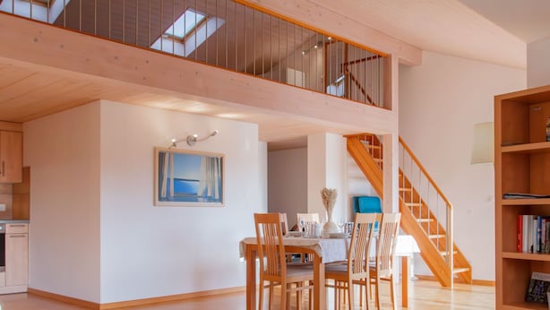 Un vaste espace de vie comprenant une table à manger pour quatre personnes, un canapé, un escalier et une bibliothèque.