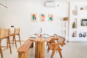 A dining area with a round wooden table set for four, surrounded by wicker chairs. - THE LUXURY LIVING (Canggu)
