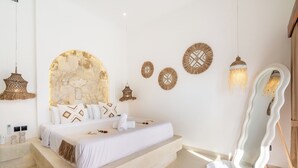 A modern bedroom with a large bed, decorative wall art, and a unique mirror. - THE LUXURY LIVING (Canggu)