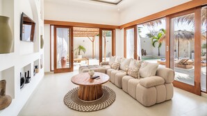 A modern living room with a sofa, coffee table, and a TV mounted on the wall. - THE LUXURY LIVING (Canggu)