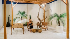 A cozy indoor seating area with a wooden bench, a round table, and a person seated. - THE LUXURY LIVING (Canggu)