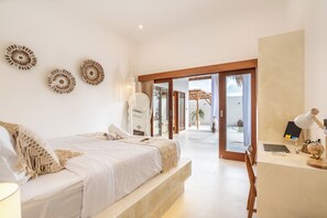 A bedroom with a large bed, a desk with a lamp, and a view of the outdoor area. - THE LUXURY LIVING (Canggu)