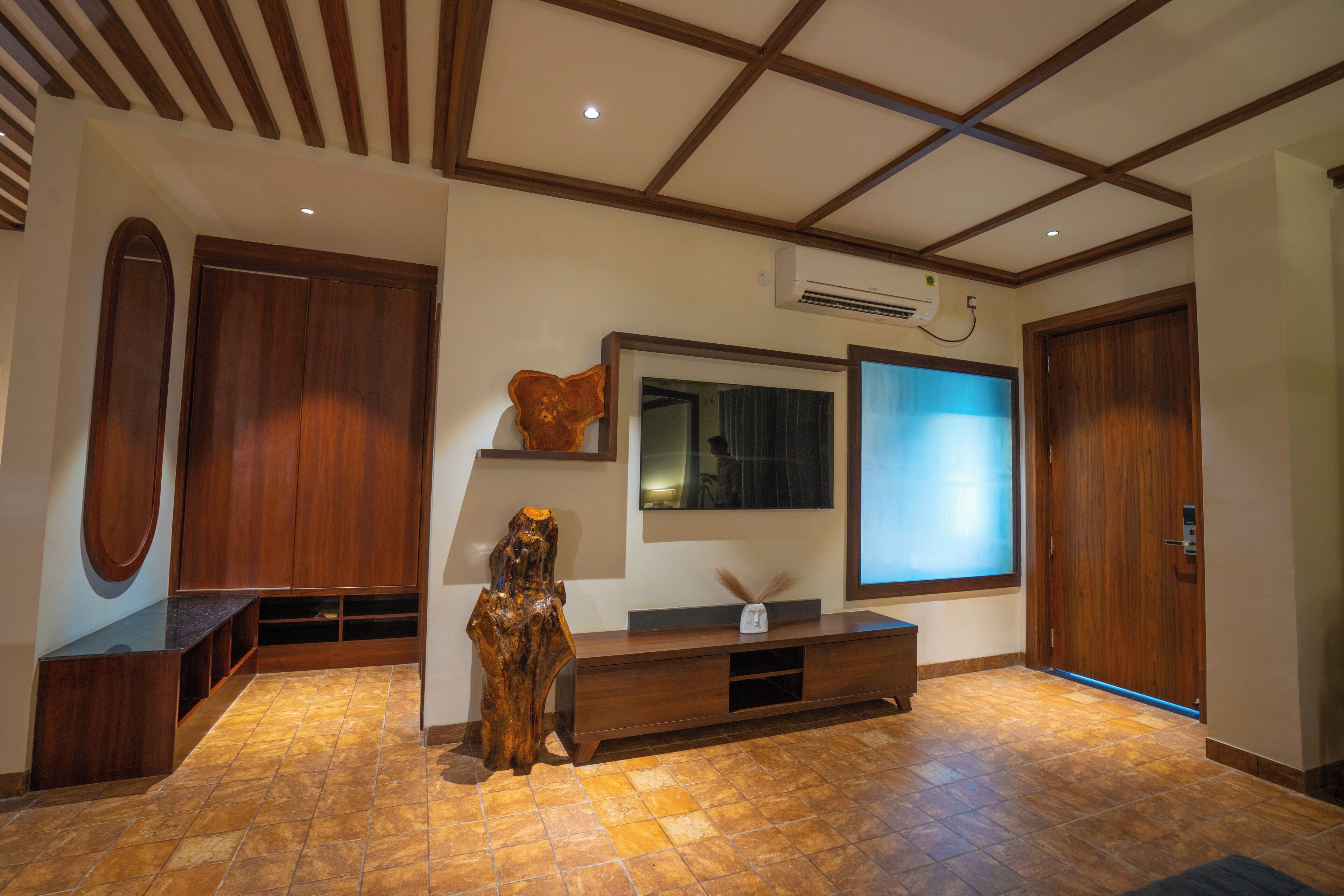 A modern living room with a wooden bench, a large flat-screen TV, and a unique wooden sculpture.