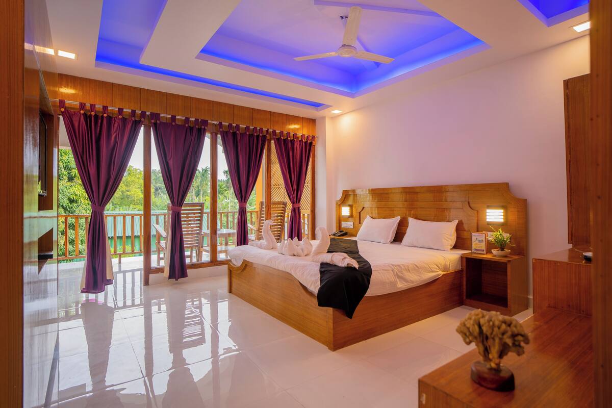 A spacious bedroom with a large bed, wooden headboard, and a nightstand with a lamp.
