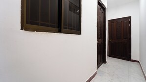 Un pasillo estrecho con un ventanal grande y una puerta de madera.