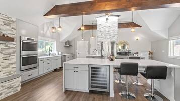 Una cocina moderna con armarios blancos, una isla grande con taburetes de bar y una viga de techo de madera.