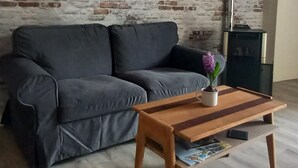 Ein Wohnzimmer mit Ziegelwand, grauem Sofa, Holztisch und einer Uhr.
