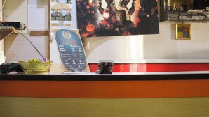 A reception desk with a framed picture of an elephant deity, a signboard with room rates, and a small decorative item on the counter. - Vibor Hotel  (Kathmandu)