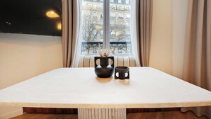 A room with a large window, a white table, a black vase, and a black mug. - Elegant Apartment - 1br/4p - Sacre-coeur (Paris)