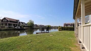 A riverside view with a grassy area, a chair, and a building with a balcony.