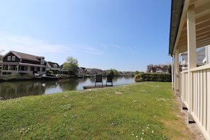 Uitzicht op een rivier met een gazon, een stoel en een gebouw met een balkon.