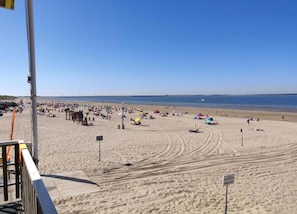 Een strand met mensen, parasols en een heldere lucht.