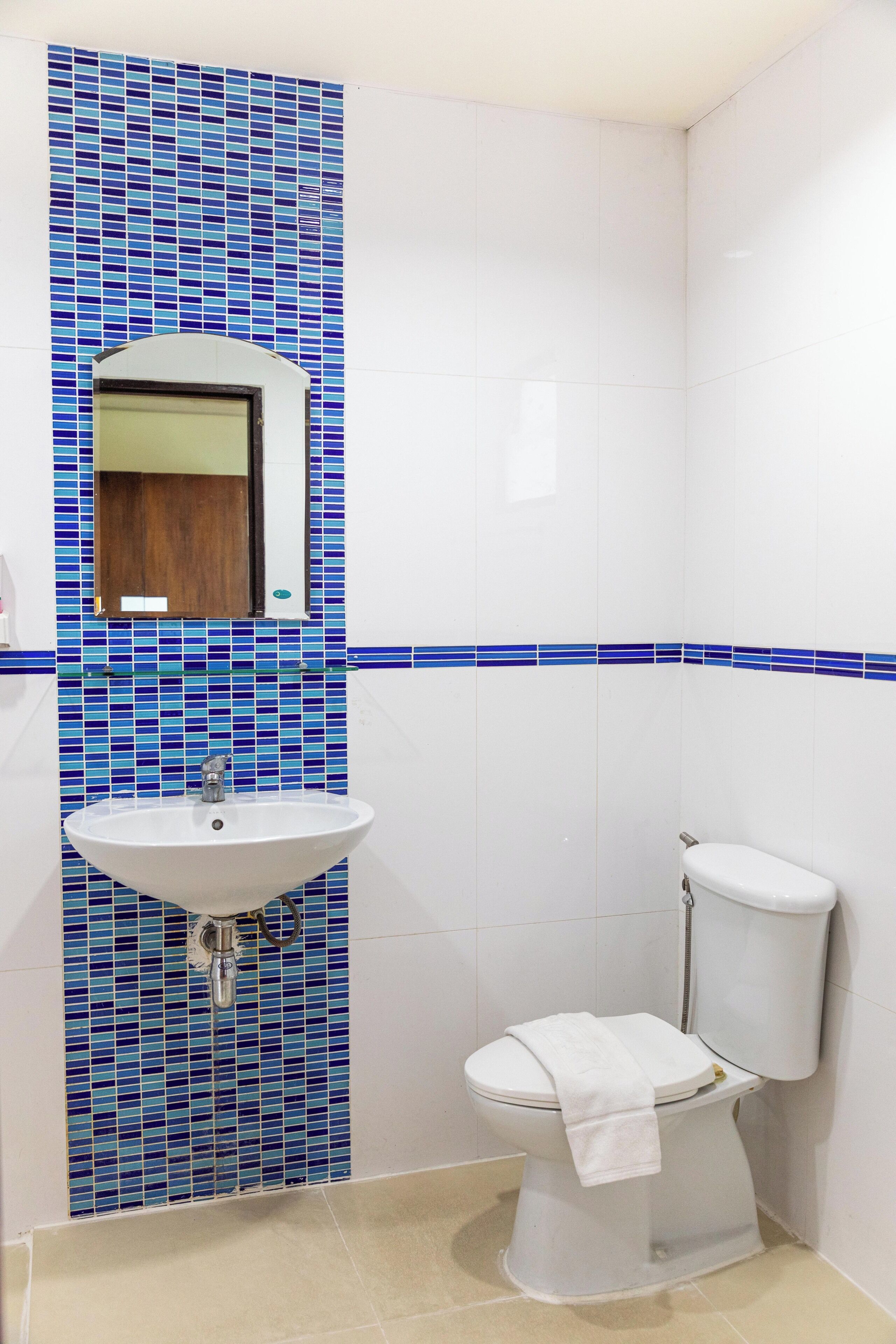 A bathroom with a sink, toilet, and mirror.