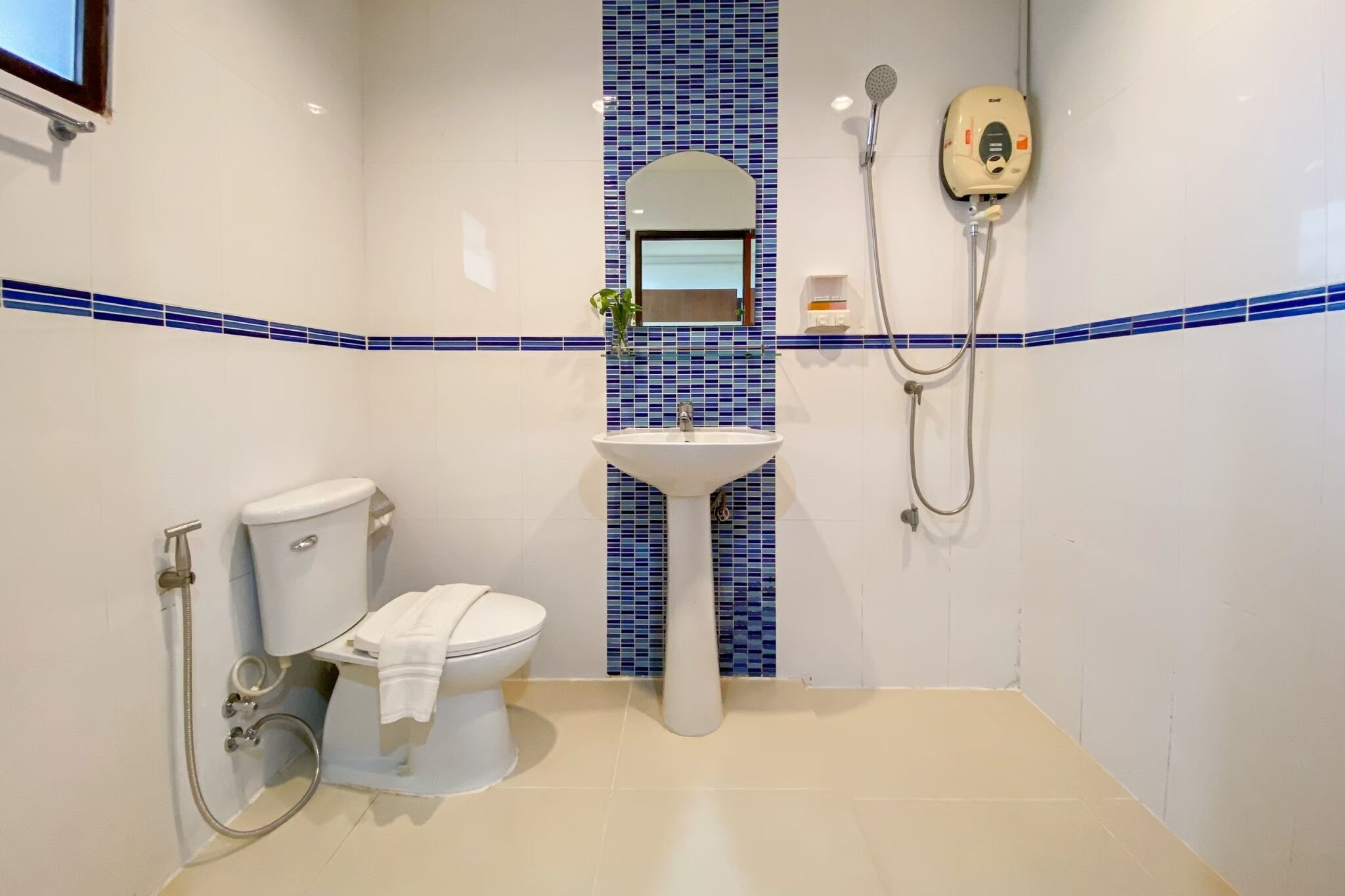 Et badeværelse med toilet, håndvask og bruser.