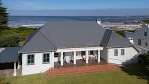 A two-story house with a covered patio and a view of the ocean.